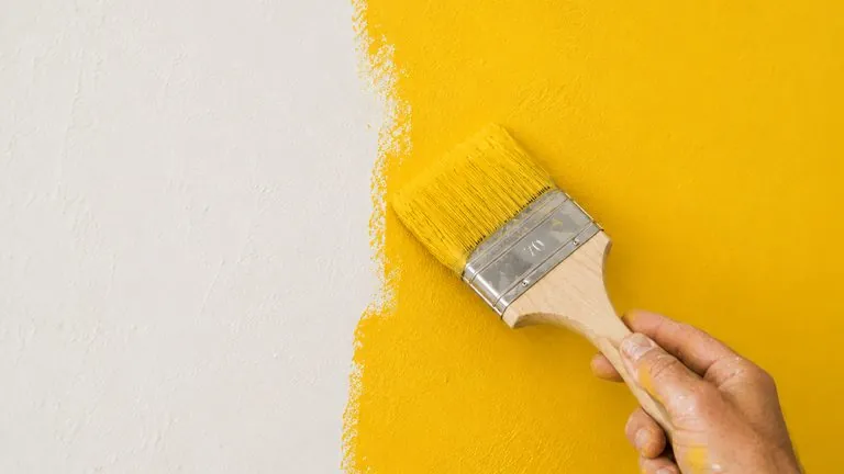 Muur schilderen met gele verf op volledig droog pleisterwerk